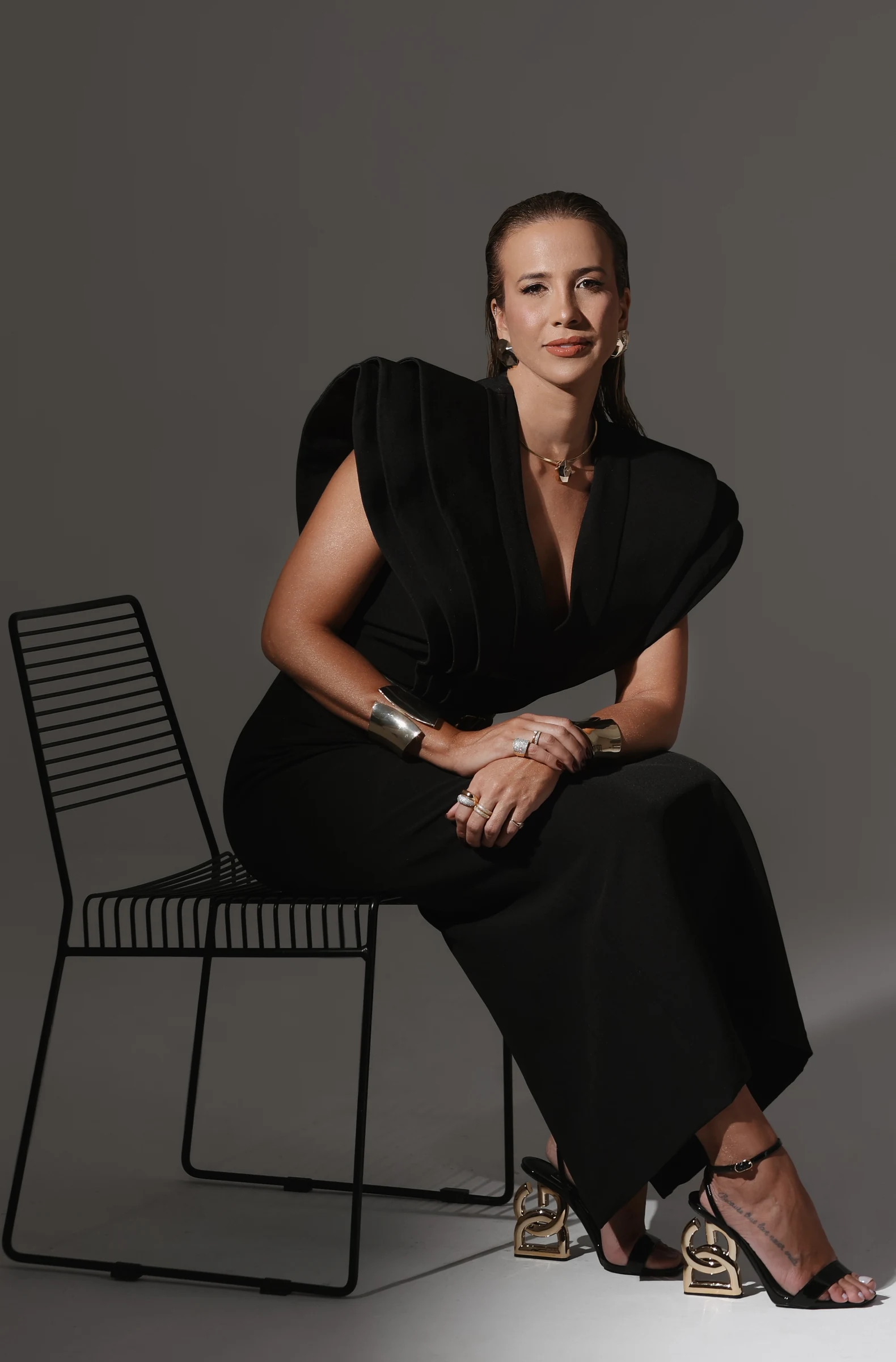Dra. Patrícia Supimpa sentada, usando vestido preto